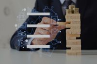 Hombre de traje juega a Jenga con monedas encima de la torre